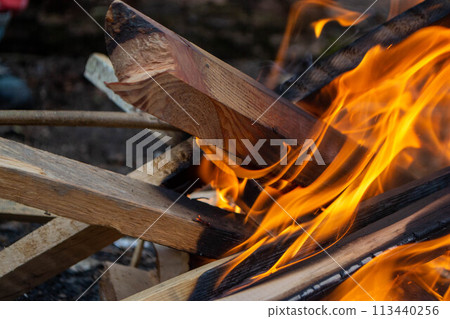 A fire burns in a campfire with a red fire in the background. A fire burns in a campfire with a red fire in the background. 113440256
