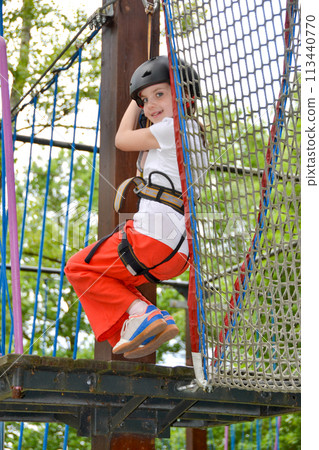 adventure climbing high wire park - people on course in mountain helmet adventure climbing high wire park - people on course in mountain helmet 113440770