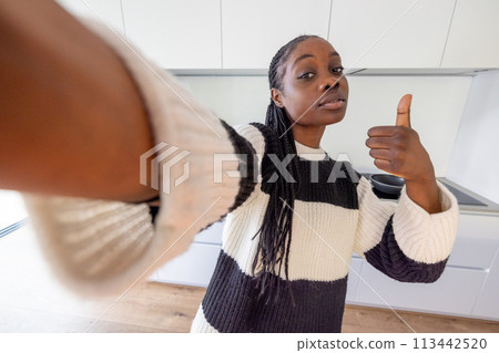 Confident Woman Giving Thumbs Up in a Selfie at Home Confident Woman Giving Thumbs Up in a Selfie at Home 113442520