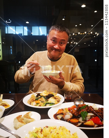 A Japanese man eating at a Chinese restaurant 113442808