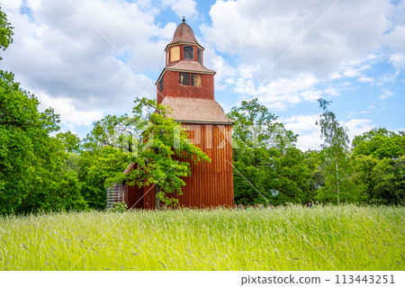 Seglora Church rustic red wooden facade stands out against the lush greenery on a bright summer day in Stockholm open-air museum, Skansen. Sweden Seglora Church rustic red wooden facade stands out against the lush greenery on a bright summer day in Stockholm open-air museum, Skansen. Sweden 113443251