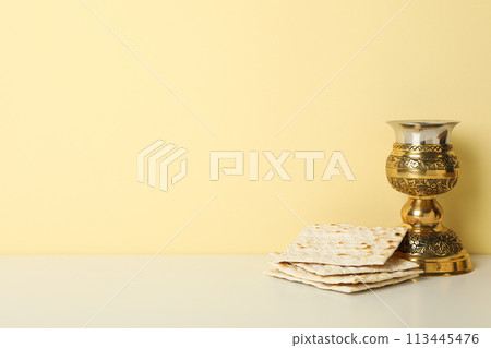Matzo and cup on light yellow background, space for text 113445476