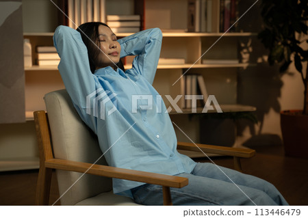 Serene Asian Woman Relaxing in a Cozy Chair Inside a Well-Lit Room Serene Asian Woman Relaxing in a Cozy Chair Inside a Well-Lit Room 113446479