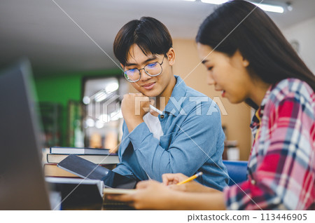 Students are consulting each other working on laptops and searching for books to study, make reports, find useful information in university room. Concept of reading, learning and intelligence. Students are consulting each other working on laptops and searching for books to study, make reports, find useful information in university room. Concept of reading, learning and intelligence. 113446905