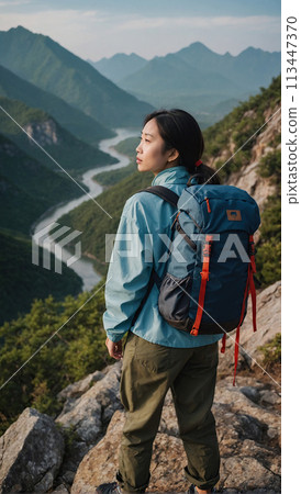 A young happy Chinese young woman with a tourist backpack stands on top of a rock in the mountains, travels and enjoys a beautiful view of the mountains, sky or nature. Untouched nature. Tourism and A young happy Chinese young woman with a tourist backpack stands on top of a rock in the mountains, travels and enjoys a beautiful view of the mountains, sky or nature. Untouched nature. Tourism and 113447370