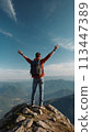 A young happy European man a tourist backpack stands on top of a rock in the mountains, travels and enjoys a beautiful view of the mountains, sky or nature. Untouched nature. Tourism and travel 113447389