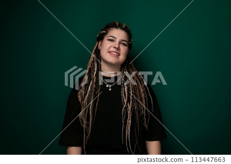Woman With Dreadlocks Standing in Front of Green Wall 113447663