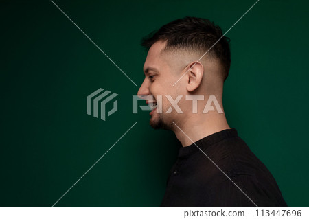 Man With Shaved Head Standing Against Green Wall 113447696