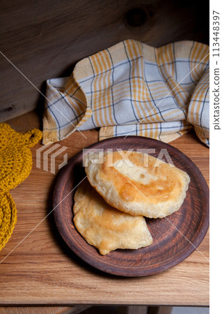 Clay plate of fried meat pies on wooden table. 113448397