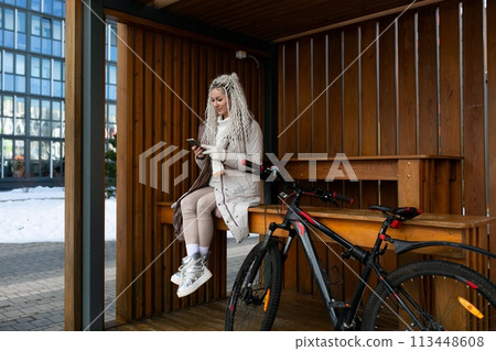 Woman Sitting on Bench Next to Bike 113448608