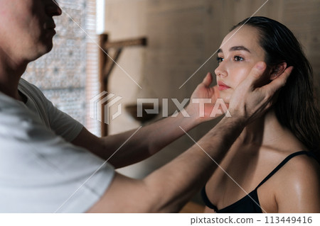 Portrait of serene young woman enjoying ear massage at spa salon. Closeup hands of unrecognizable masseur massaging auricle of beautiful female client sitting on massage table in wellness center. Portrait of serene young woman enjoying ear massage at spa salon. Closeup hands of unrecognizable masseur massaging auricle of beautiful female client sitting on massage table in wellness center. 113449416