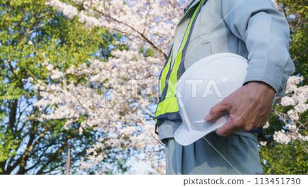 A man in work clothes with cherry blossoms and a helmet 113451730