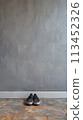 A pair of shoes sitting on a tile floor in front of a wall, AI 113452326