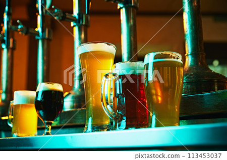 Row of beer glasses on bar counter filled with different types of beer, showing variety in taste 113453037