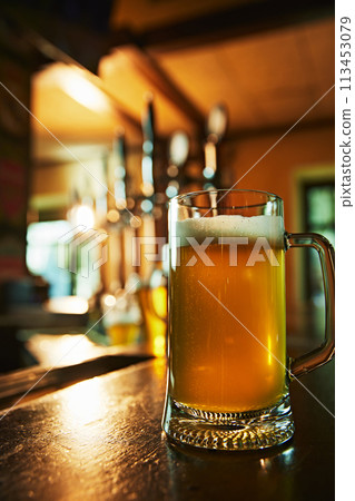Glass with foamy lager beer on wooden table at cozy bar atmosphere on background. Refreshing and satisfying drink. 113453079