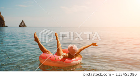 Summer vacation woman in hat floats on an inflatable donut mattress. Happy woman relaxing and enjoying family summer travel holidays travel on the sea. 113453080