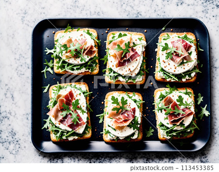 A tray filled with small sandwiches topped with various ingredients such as ham, cheese, lettuce, and tomato. A tray filled with small sandwiches topped with various ingredients such as ham, cheese, lettuce, and tomato. 113453385