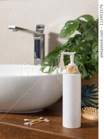 White one pump bottle near basin and green monstera on wooden countertop in bath, mockup White one pump bottle near basin and green monstera on wooden countertop in bath, mockup 113453579