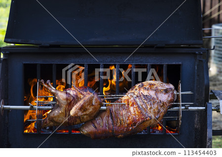 Roasting pork and turkey on spit Roasting pork and turkey on spit 113454403