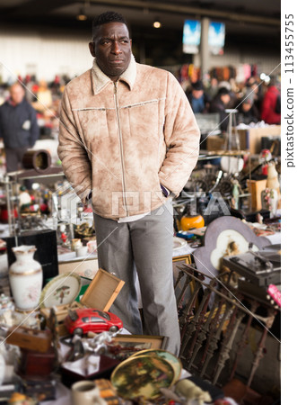 Ordinary afro-american seller in a flea market is waiting for buyers Ordinary afro-american seller in a flea market is waiting for buyers 113455755