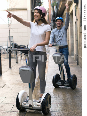Young couple guy and girl walking on segway in streets of european city 113455760