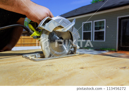 Using handsaw, carpenter trims plywood boards Using handsaw, carpenter trims plywood boards 113456272