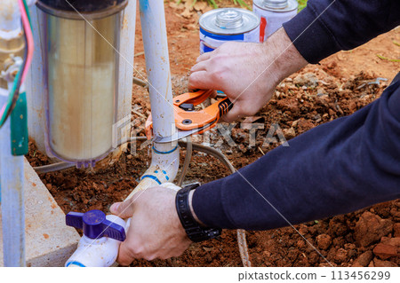 Technician plumber uses special scissors to cut plastic PVC pipe during repair work Technician plumber uses special scissors to cut plastic PVC pipe during repair work 113456299