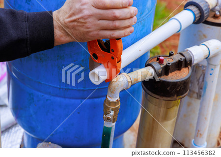 Using special pair of scissors, plumber cuts plastic PVC pipe Using special pair of scissors, plumber cuts plastic PVC pipe 113456382