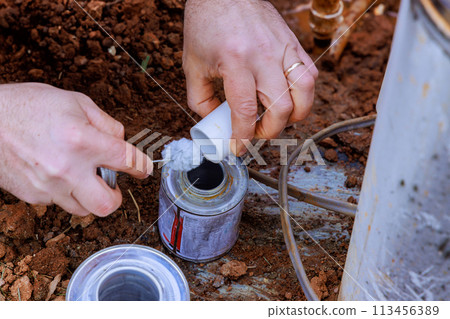 Plumbers use clear primer for PVC pipes before gluing them before completing repair work 113456389