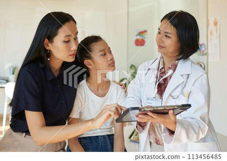 Pediatrician showing medical tests results to mother of sick patient Pediatrician showing medical tests results to mother of sick patient 113456485