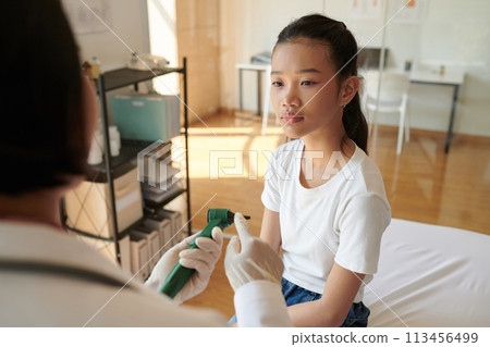 Otolaryngologist explaining teenage girl how otoscope works before examining her ears Otolaryngologist explaining teenage girl how otoscope works before examining her ears 113456499