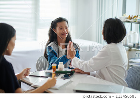 Smiling Vietnamese teenage girl giving high five her therapist celebrating recovery 113456595