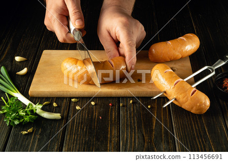 The chef is preparing Vienna sausages on the kitchen board. Low key grilling concept with sausages and aromatic spices. European cuisine 113456691
