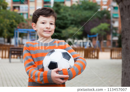 Boy holding soccer ball outdoors 113457007