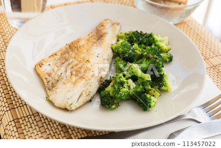 Fried fillet of sea bass with garnish of broccoli on black warm stone plate Fried fillet of sea bass with garnish of broccoli on black warm stone plate 113457022