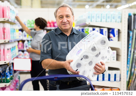 Elderly man chooses toilet paper in supermarket 113457032