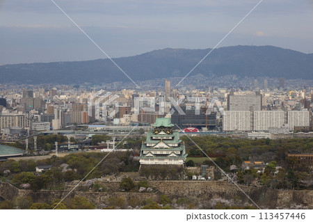 Bird's-eye view of Osaka Castle from the sky Cherry blossom season Ikoma mountain range Cherry blossoms in full bloom against the blue spring sky 113457446