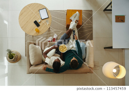 Young couple eating popcorn and watching tv at home, view from the top 113457459