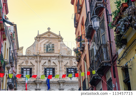 Cagliari San Michele Jesuit Catholic church facade around historic buildings with wooden window shutters and iron balconies in Sardinia Island, Italy. 113457715