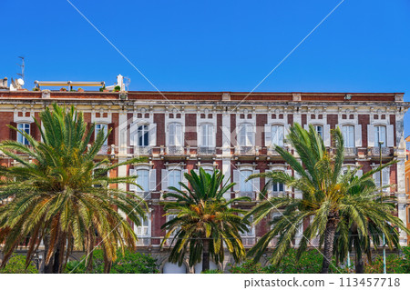 Cagliari waterfront historic buildings facade with wooden window shutters and iron balconies under clear blue sky in Sardinia Island, Italy. 113457718