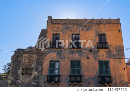 Cagliari citadel old building facade with wooden window shutters, iron balconies and decayed facade in Sardinia Island, Italy. 113457723