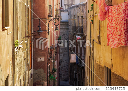 Cagliari citadel alley with traditional buildings with iron balconies and Italian flag waving in Sardinia Island, Italy. 113457725