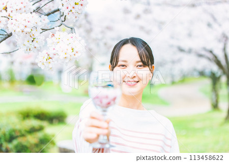Woman holding a wine glass filled with cherry blossom petals Woman holding a wine glass filled with cherry blossom petals 113458622