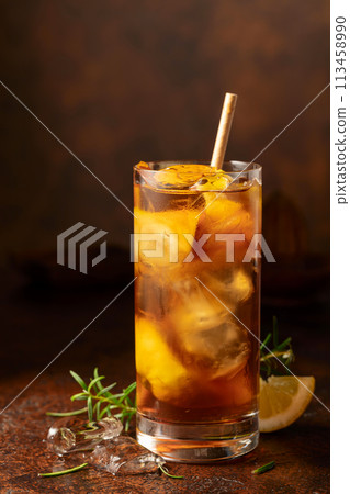 Iced tea or cocktail with ice, rosemary and lemon slices on the old brown table. 113458990