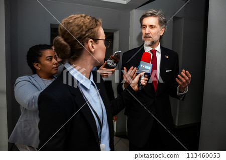 Busy republican politician gives interview for TV news in corridor 113460053
