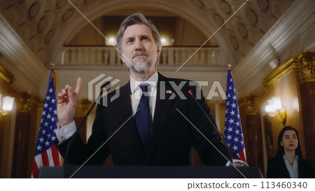 Mature US minister or politician speaks at press conference for media in White House 113460340