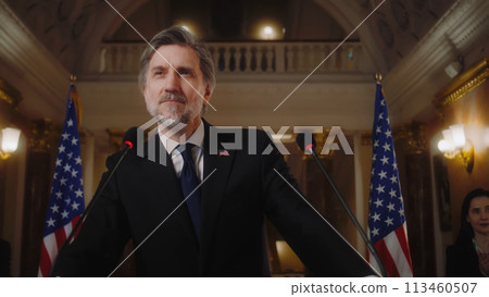 Confident US minister or congressman smiles, poses for cameras after political speech Confident US minister or congressman smiles, poses for cameras after political speech 113460507