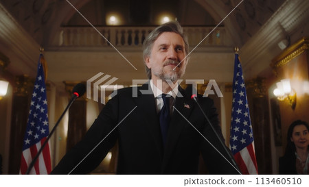 Confident US minister or congressman smiles, poses for cameras after political speech Confident US minister or congressman smiles, poses for cameras after political speech 113460510