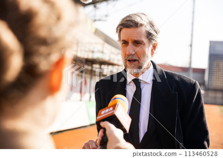 Interview of private investor for TV news in soccer stadium 113460528