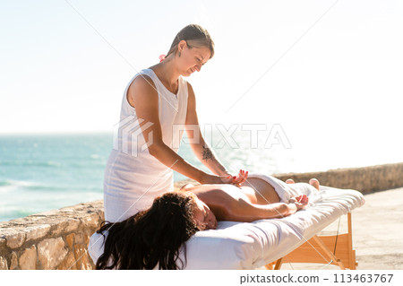 Woman enjoying hand and back massage on ocean Woman enjoying hand and back massage on ocean 113463767